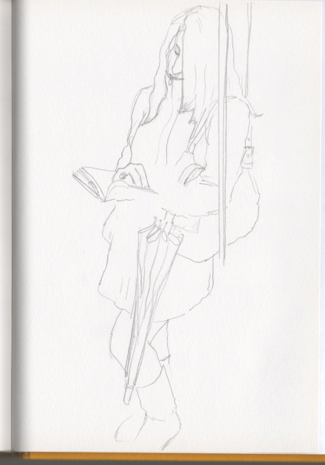 Chica abrigad�sima (hac�a fr�o), leyendo de pi�, llevando un paraguas enganchado del bolso, en un vag�n del metro Bilbao.